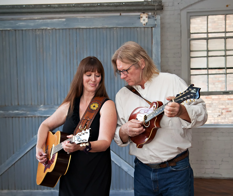 Bruce and Becca Ling standing with their guitar and mandolin. 